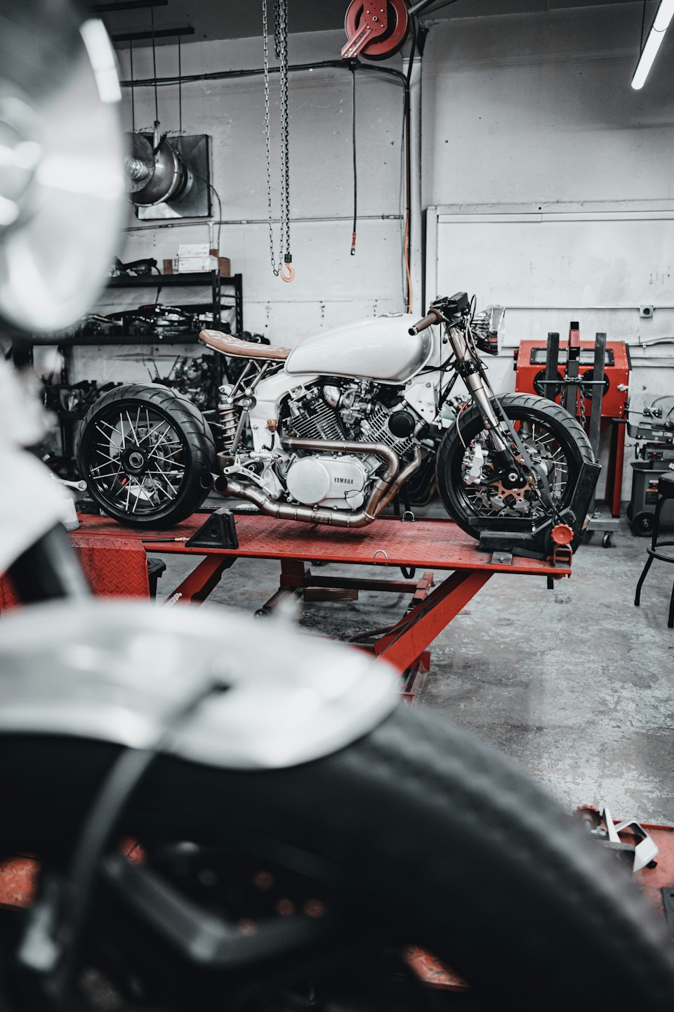 Weißes Motorrad auf einer Hebebühne in einer Werkstatt.